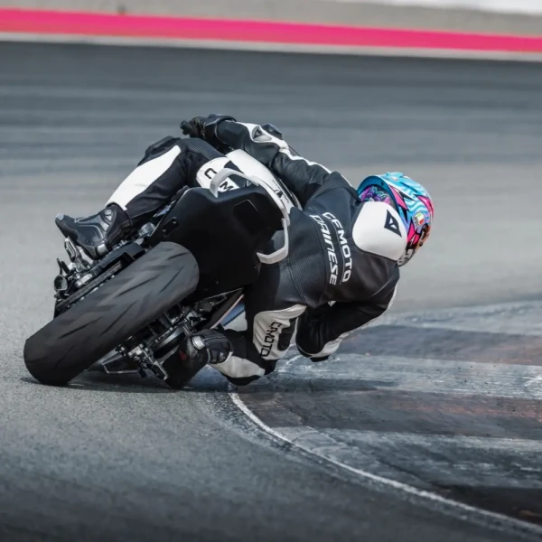 0176_YM24_CFMoto_675SR-R_v3_2 A motorcyclist in black and white racing gear leans sharply into a turn on a racetrack, showcasing the thrill of track day with high-performance racing motorcycles.