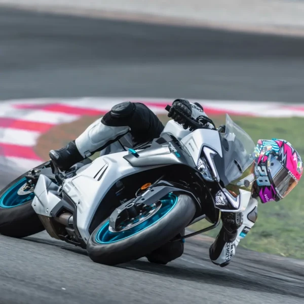 0194_YM24_CFMoto_675SR-R_v3_2 A motorcyclist in full gear leans sharply while riding a white racing motorcycle on a racetrack during a thrilling track day.