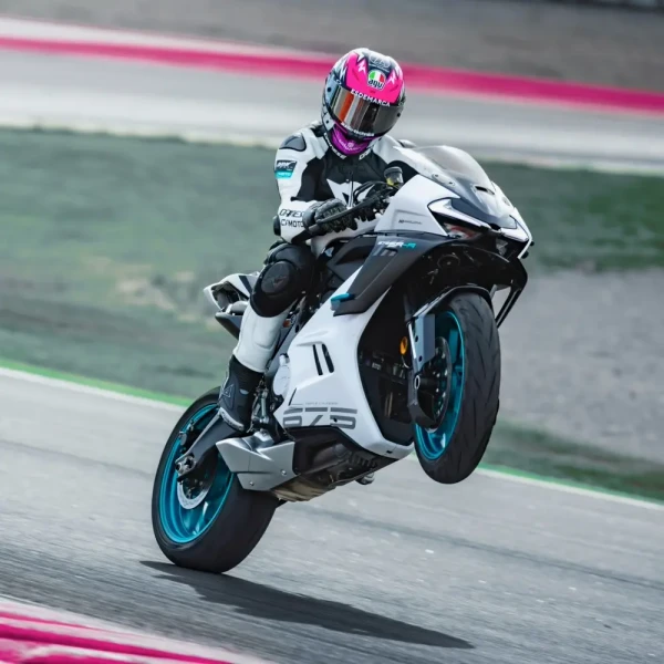 0223_YM24_CFMoto_675SR-R_v3_2 A motorcyclist in full gear performs a wheelie on a white and blue racing motorcycle during an exhilarating track day.