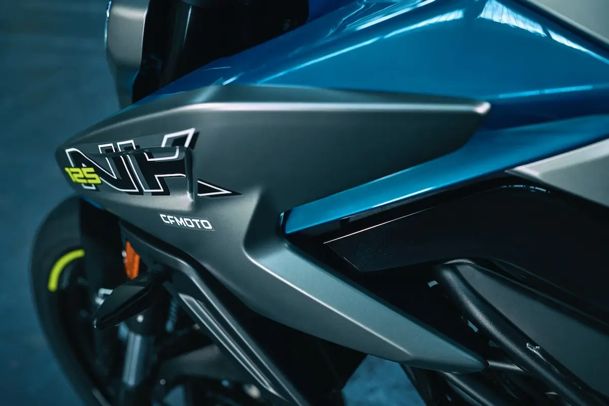 Close-up view of a blue CFMOTO 125NK motorcycle, highlighting the side fairing with the "125" model designation and logo.