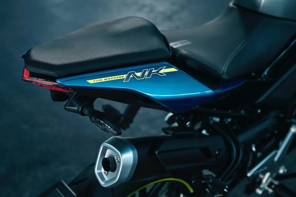 Close-up of the rear seat and exhaust of a blue 125NK motorcycle with a "NK" decal and "Fun Machine" text visible on the side panel.