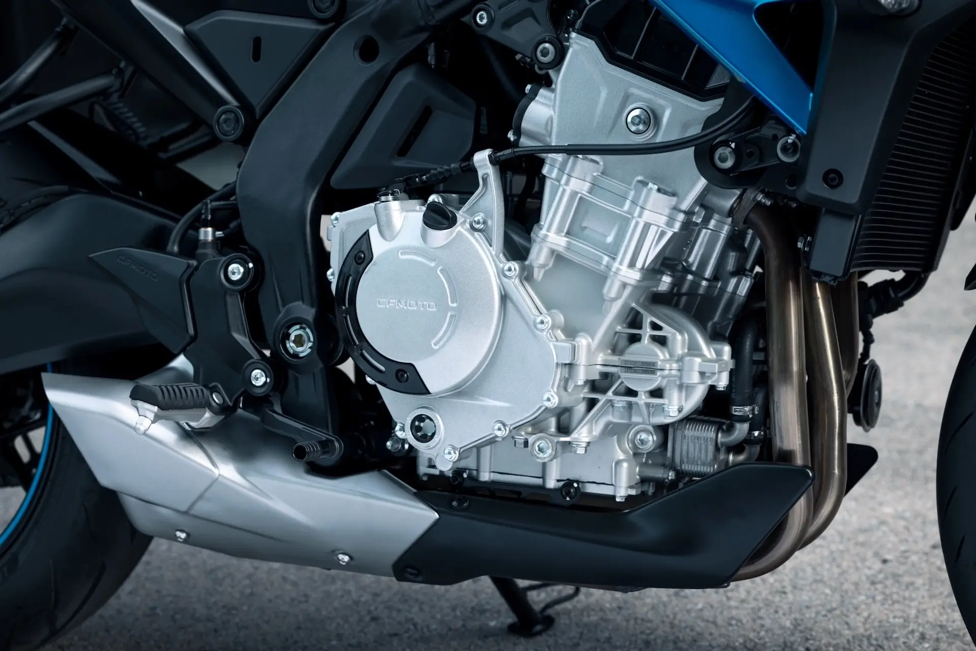 Close-up view of a 125NK motorcycle engine, showing metallic components, bolts, and part of the motorcycle frame.