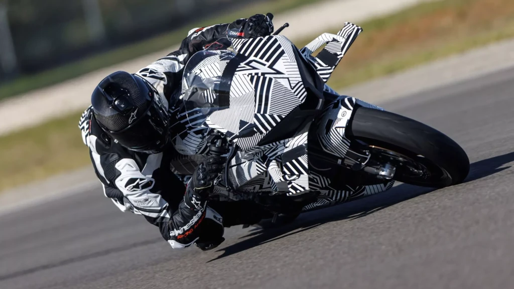 A motorcyclist in full gear leans sharply into a turn on a track, riding a sport bike with black and white camouflage graphics inspired by the CFMOTO CFORCE TECH GEN 4 Concept.