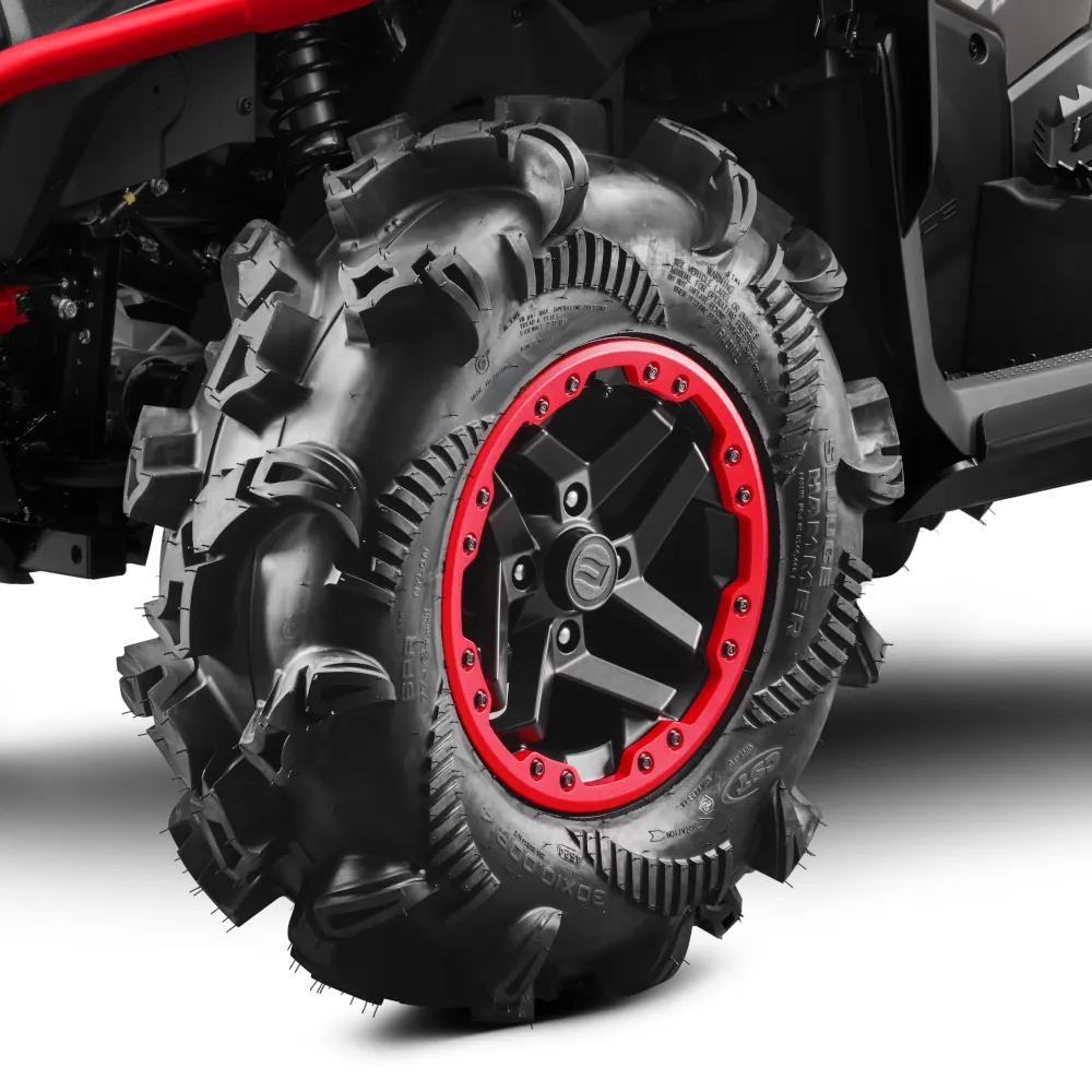 Close-up view of a rugged CFORCE 1000 MV off-road vehicle tire with deep treads and a striking red and black rim, mounted on a vehicle.