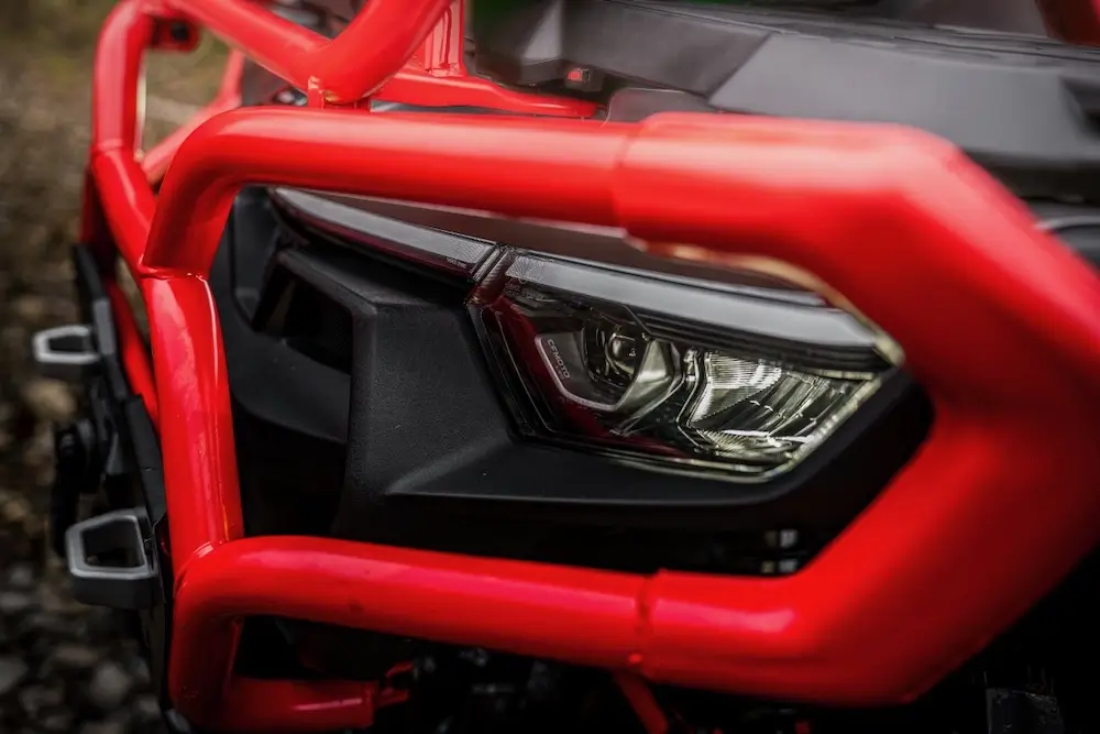 Close-up of a UFORCE U10 XL PRO headlight with a red metal protective guard, highlighting the rugged front design.