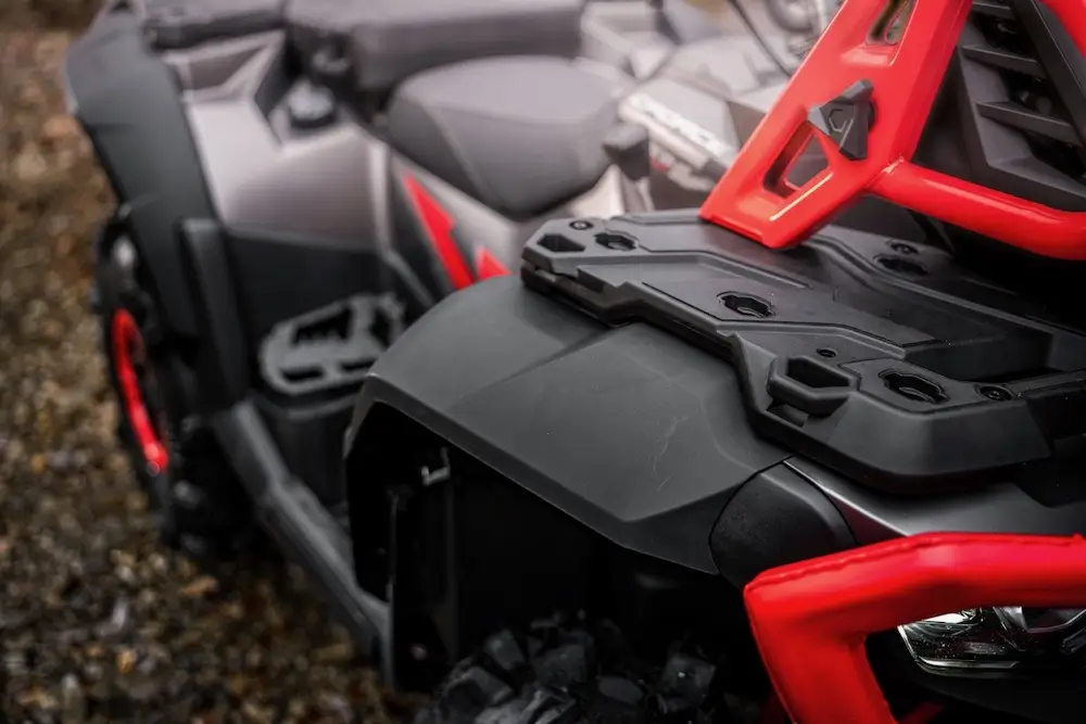 Close-up view of the front section of a UFORCE U10 XL PRO all-terrain vehicle (ATV) featuring black and red detailing and rugged components.