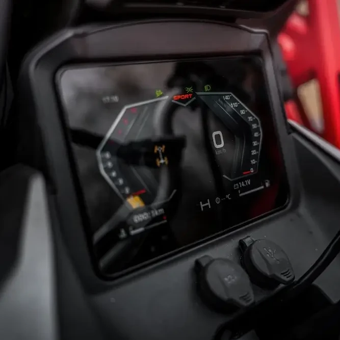 Close-up of a CFORCE 1000 MV digital motorcycle dashboard display showing speed, indicators, and gauges; two power outlets are visible below the screen.
