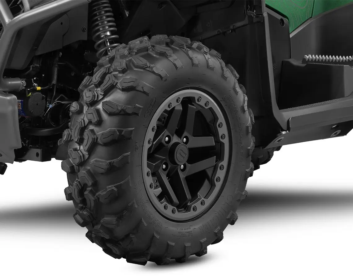 Close-up of a rugged off-road vehicle tire with deep treads and a black alloy wheel, showcasing the suspension and a portion of the frame. This dynamic setup is reminiscent of the durability you'd expect from a CForce 1000 Touring Premium design.