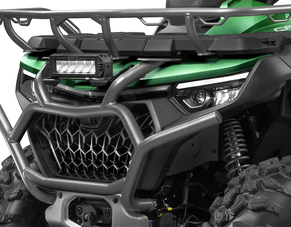 Close-up of a green CForce 1000 Touring ATV featuring a black metal grille, rugged headlights, and a protective bumper with a mounted light bar.