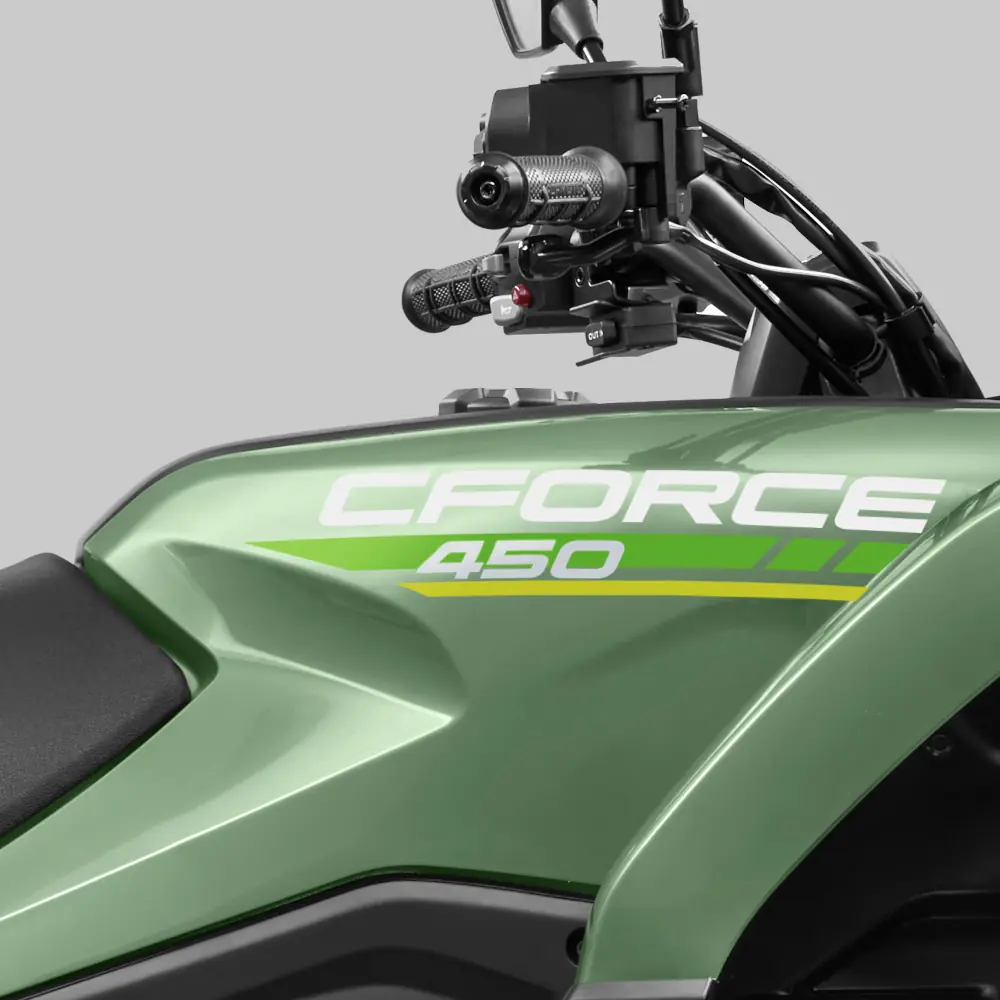 Close-up of a green CFMOTO cforce 450 ATV, showcasing its handlebars and part of the seat against a plain gray background.
