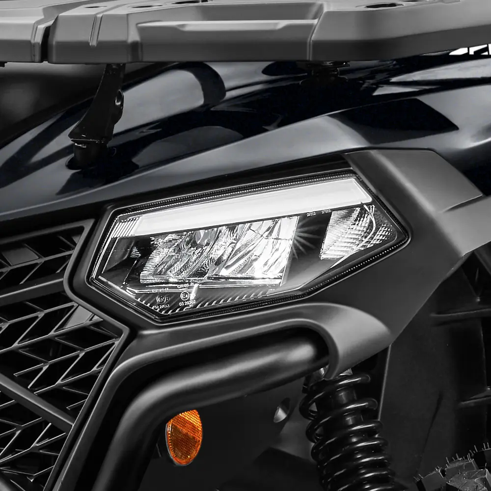 Close-up of a black CForce 520 all-terrain vehicle (ATV) front headlight, showing the grille, suspension, and part of the cargo rack.