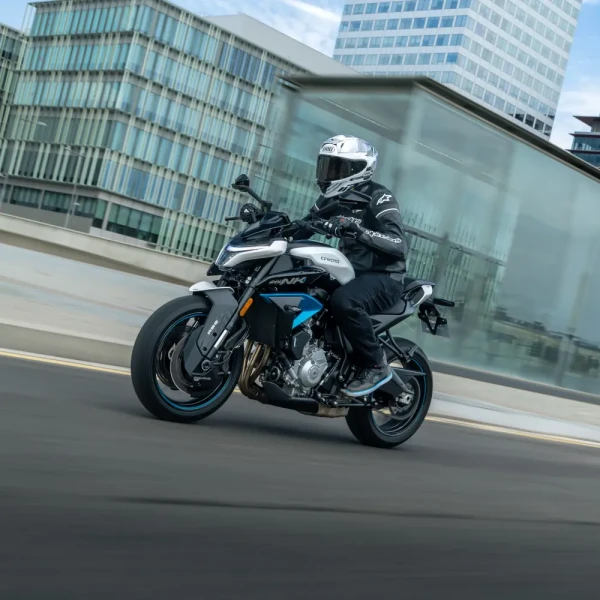 Commuter motorcycles 5 A motorcyclist in full riding gear enjoys leisure riding on a white and blue sport motorcycle through an urban road, framed by modern glass buildings in the background.