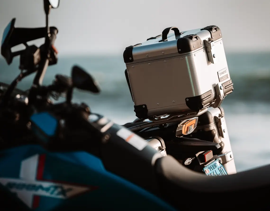 A close-up of an 800MT-X motorcycle equipped with a large silver storage box on the rear, parked outdoors with a blurred background.