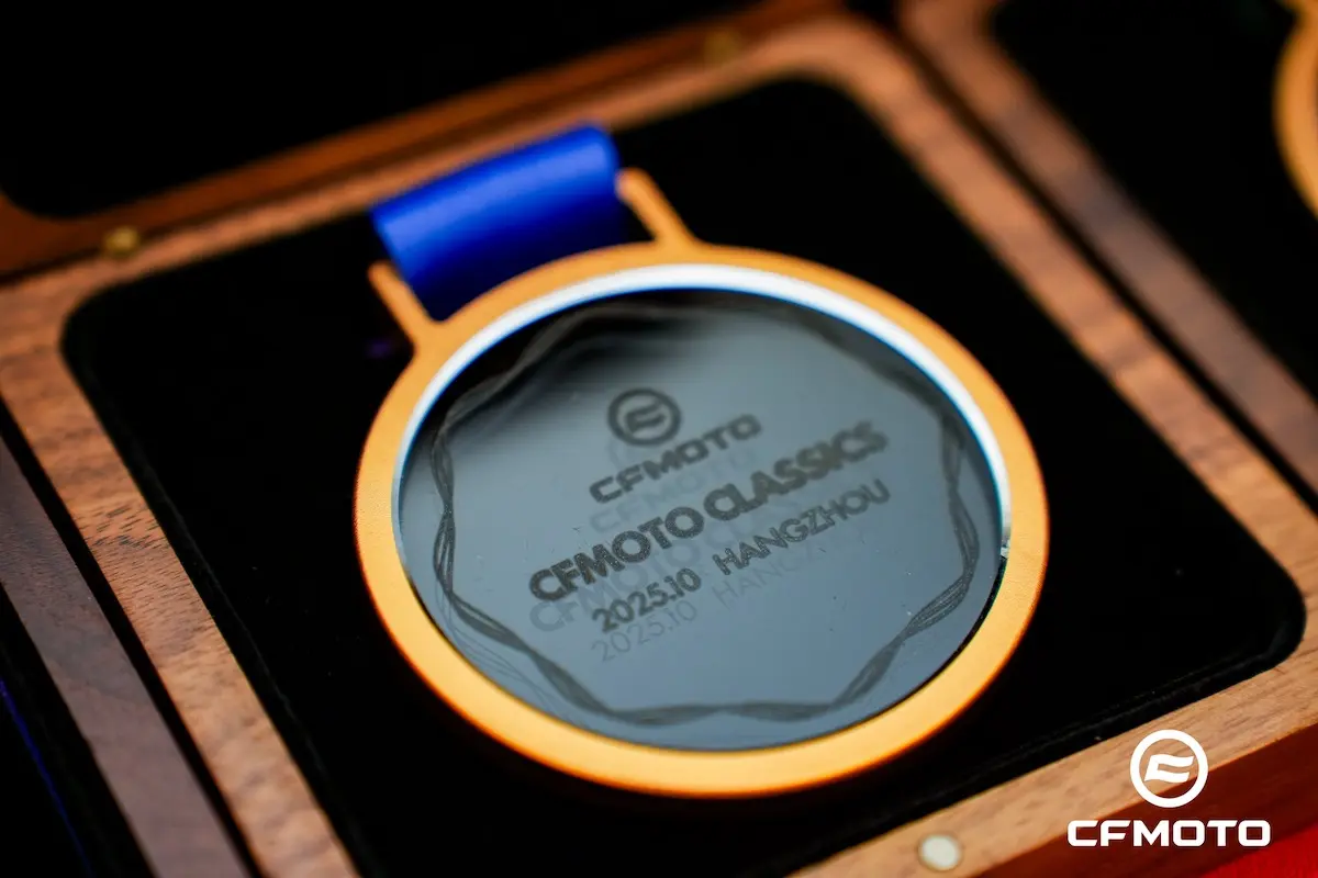 A close-up of a CFMOTO Classics medal with a blue ribbon, engraved with "CFMOTO Classics 202310 HANGZHOU," highlighting the brand’s commitment to ATV safety, presented in a wooden box.