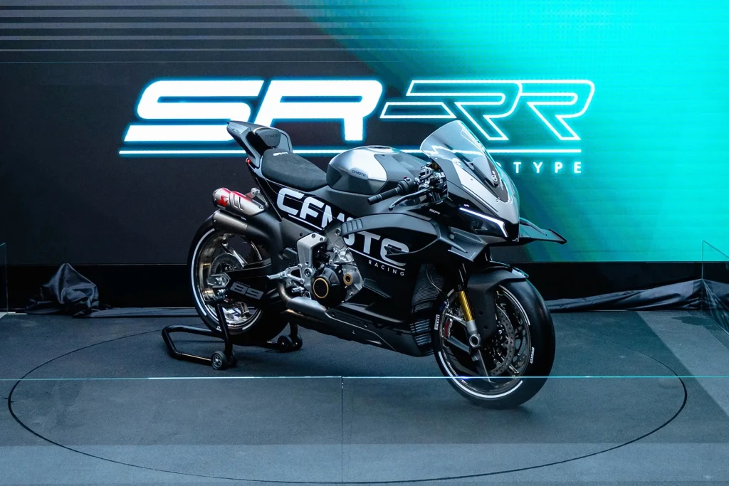 A high-performance black and silver sports motorcycle is displayed on a platform in front of a digital SR-RR Type sign, echoing the innovation of the CFMOTO CFORCE TECH GEN 4 Concept.