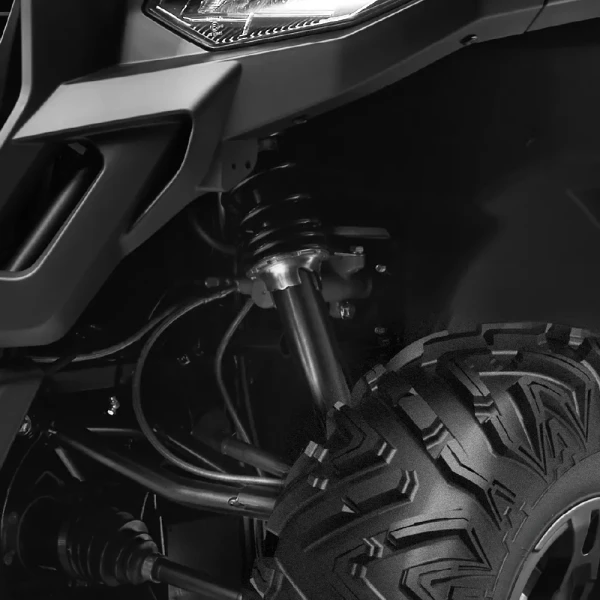 Close-up view of a rugged UFORCE 600's front suspension system and tire, showing detailed shock absorber, coil spring, and tread pattern.