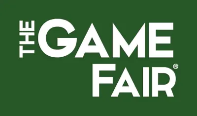 White text on a dark green background reads "THE GAME FAIR," with "THE" written vertically to the left of "GAME FAIR," visually highlighting the Game Fair event.
