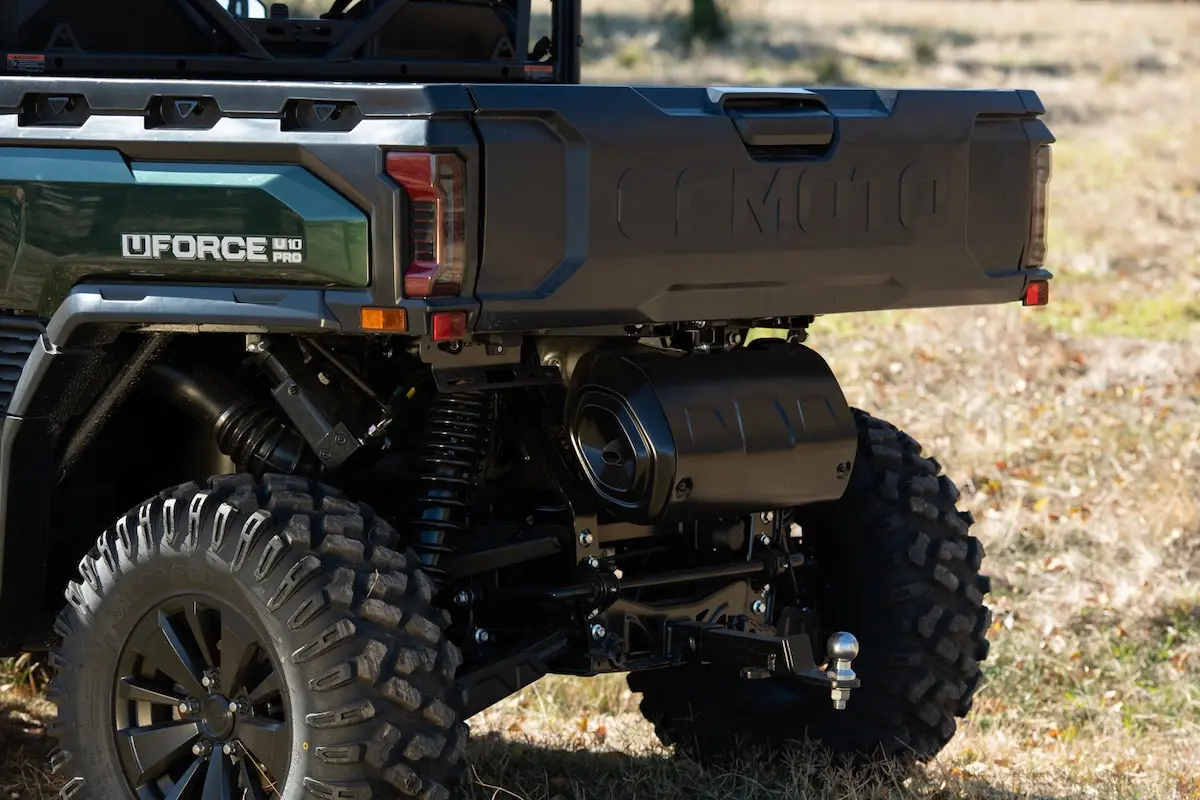 Close-up view of the rear suspension, wheels, and cargo bed of a green UFORCE U10 PRO AGRI utility vehicle parked outdoors on grass.