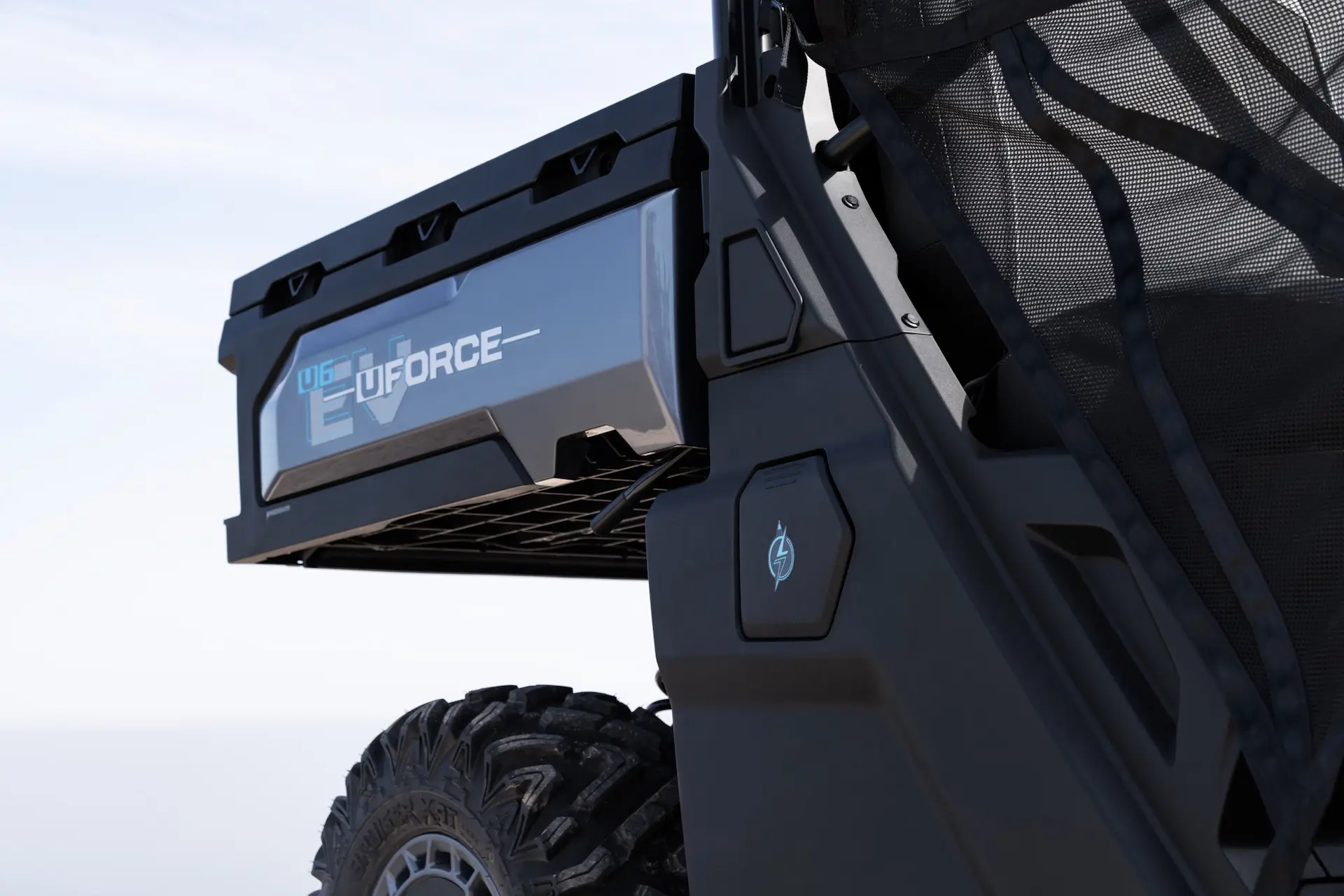 Close-up of a UFORCE 600 utility vehicle showing the rear cargo bed, tire, and door panel, with a mesh barrier visible on the right side.