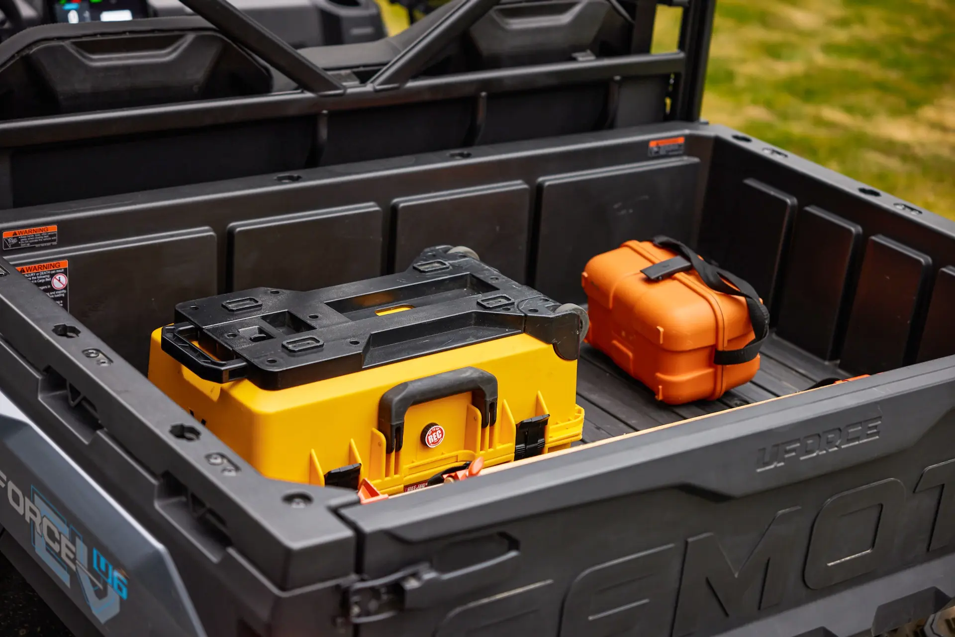A black uforce 600 truck bed with a large yellow toolbox and a smaller orange hard case placed inside.