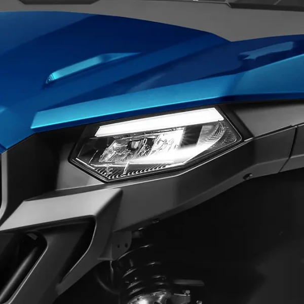 Close-up of a uforce 600’s modern, angular headlight with a blue exterior, highlighting the visible suspension components underneath.