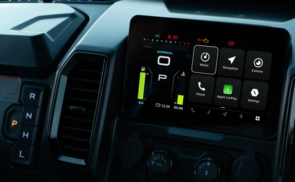 Close-up of a vehicle dashboard display, often found in ATVs and UTVs used in agriculture, showing gear selection, digital gauges, and a touchscreen with media, navigation, phone, and settings icons.