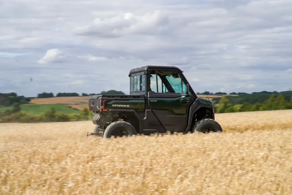 UTV safety on the farm A black utility vehicle follows ATV safety guidelines as it drives through a golden wheat field under a cloudy sky, with green hills in the background.