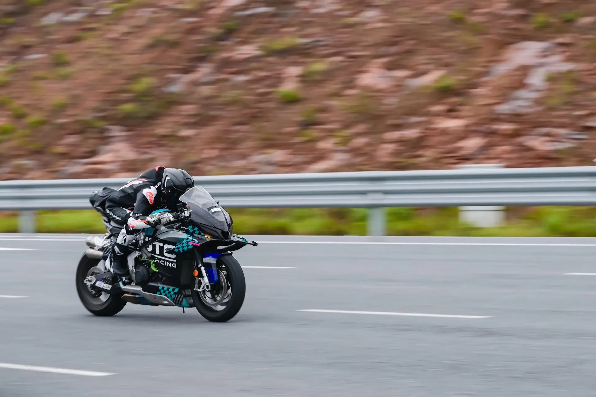 A motorcyclist in racing gear rides a black CFMOTO V4 SR-RR sportbike at top speed on a tarmacked road, approaching 315.82 km/h with the background blurred by motion.
