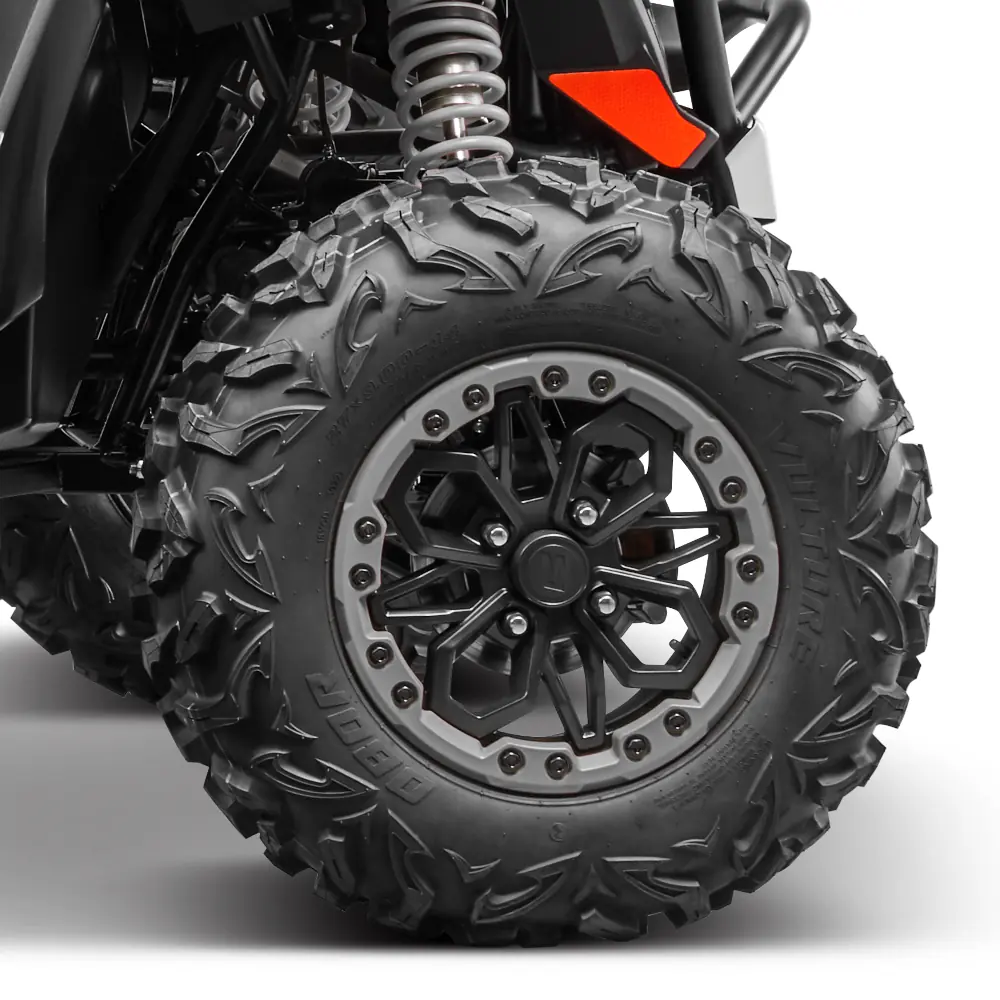 Close-up view of a rugged zforce 950 sport 4 off-road vehicle tire and black alloy wheel with visible suspension spring and part of the vehicle's body.
